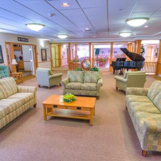A spacious and well-lit living room featuring multiple sofas, a coffee table, and a grand piano.