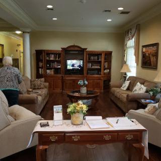 A cozy living room featuring comfortable sofas and a wooden bookcase, with a television in the background.
