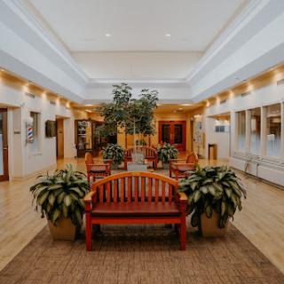 A spacious and welcoming lobby featuring wooden benches, indoor plants, and bright lighting, perfect for relaxation.