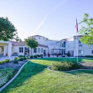 A sunny day view of a large building with a well-maintained lawn and greenery.