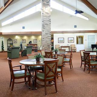 A spacious and well-lit interior room featuring multiple tables and chairs arranged for communal seating.