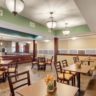 A spacious dining area with wooden tables and chairs, well-lit by ceiling lights.