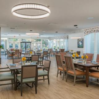 A spacious dining area with neatly arranged tables and chairs, featuring modern lighting fixtures.