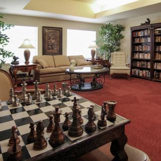 A cozy living room with a large chess set, comfortable sofa, and a bookshelf filled with books.