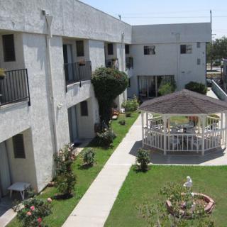 A view of an apartment complex courtyard featuring a central gazebo and landscaped grass areas.