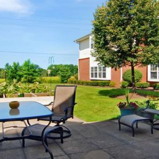 A sunny backyard patio with outdoor furniture and a landscaped garden.