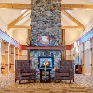 A cozy lobby with a stone fireplace and comfortable armchairs, accented by wooden beams.