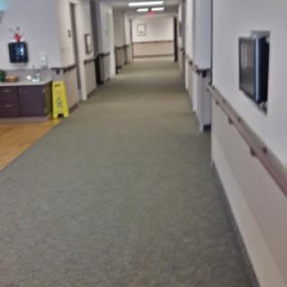 A well-lit hallway within a healthcare facility, showcasing clean carpeting and clear passage.