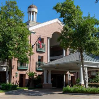A charming brick hotel entrance with surrounding trees and flags displayed.