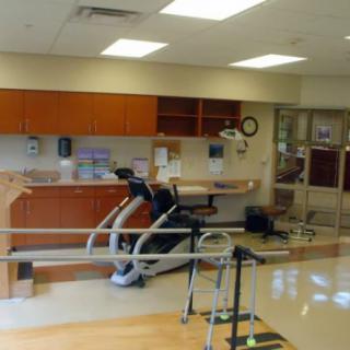A physical therapy room equipped with various exercise machines and equipment in a healthcare facility.