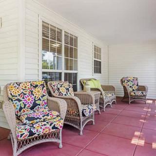 A cozy porch featuring wicker chairs with colorful, floral-patterned cushions.
