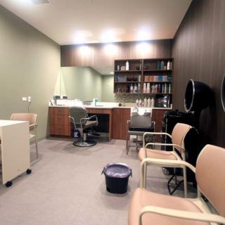 A modern salon interior with chairs, a mirror, and shelves stocked with hair products.