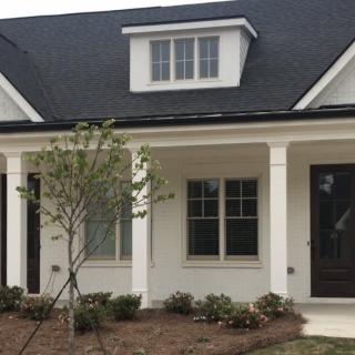 A front view of a residential house with a porch and landscaping.