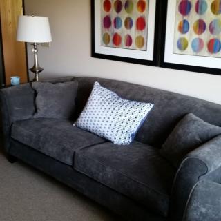 A cozy living room setup featuring a modern gray sofa with decorative pillows and colorful artwork.