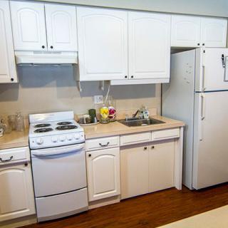 A clean and organized kitchen featuring white cabinets, a stove, refrigerator, and sink.