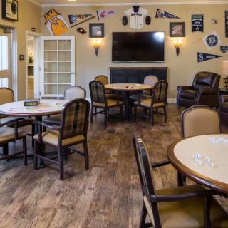 A cozy interior with tables and chairs facing a television, decorated with wall art.