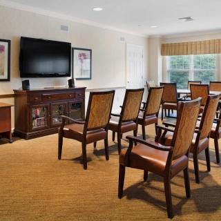 A small conference room with rows of chairs facing a television on the wall.
