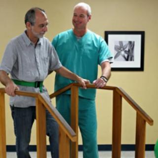 A medical professional assists an elderly man during a physical therapy session.