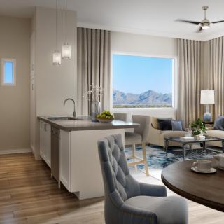 A modern open-plan living space featuring a kitchen, dining area, and cozy living room with a large window offering a stunning mountain view.