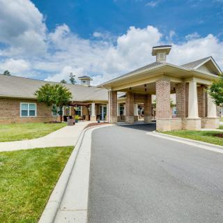 A view of a building with a driveway and entrance under a partly cloudy sky.