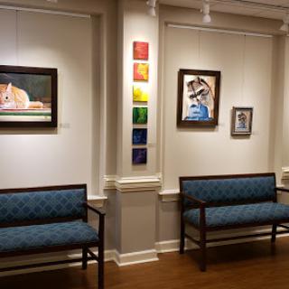 A view of an art gallery featuring various paintings and comfortable seating.