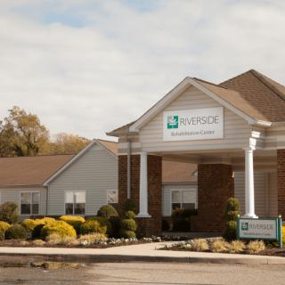A healthcare clinic building with a parking lot in front, captured during the daytime.