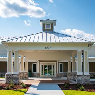A modern building entrance with a covered porch and landscaped surroundings.