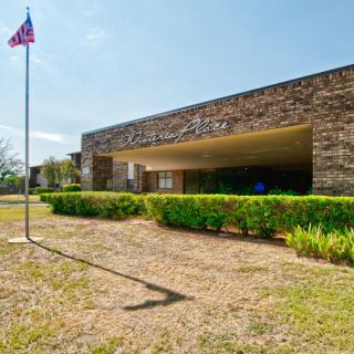 Exterior view of a building entrance with a flagpole and landscaped surroundings.