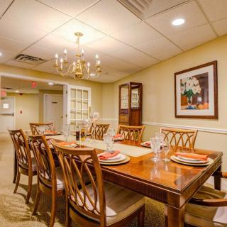 A well-appointed dining room with a wooden table set for a meal, surrounded by matching chairs and illuminated by an elegant chandelier.