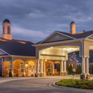 A well-lit building entrance with a driveway during the evening.