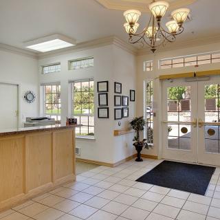 A bright and welcoming reception area with tiled flooring, a chandelier, and framed decorations on the wall.