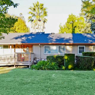 A cozy suburban house with a well-maintained lawn and surrounding trees.