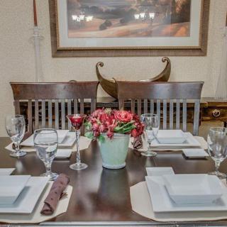 A beautifully set dining table with elegant square plates and a floral centerpiece.