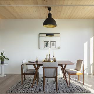 A modern dining room with a minimalist design, featuring a wooden table, chairs, and decorative elements.
