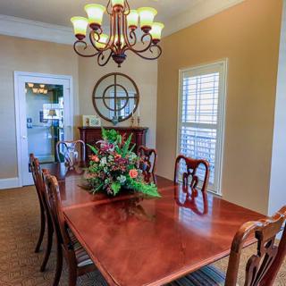 A stylish dining room featuring a wooden table adorned with a floral centerpiece, elegant chairs, and a classic chandelier overhead.