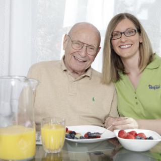 A joyful moment shared over breakfast between an elderly man and a young woman.