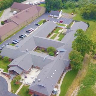 Aerial view of a multi-building complex surrounded by green areas and a parking lot.