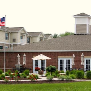 A welcoming residential building featuring well-maintained landscaping and an American flag.