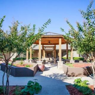 A well-landscaped building entrance with trees and a pathway leading inside.