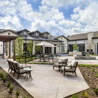 A modern outdoor patio area with comfortable seating and a scenic view of the adjacent building under a partly cloudy sky.