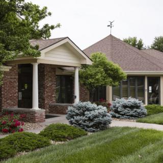 A suburban brick house with well-maintained landscaping and a lush green lawn.