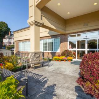 The entrance of a building featuring landscaped flower beds and seating.