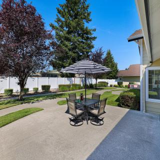 A sunny backyard patio with a table, chairs, and an umbrella.