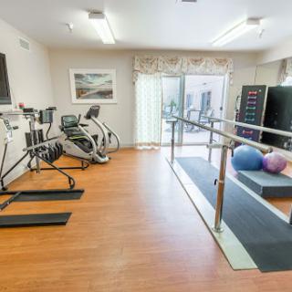 A modern fitness and rehabilitation room equipped with various exercise machines, balance bars, and stability balls.