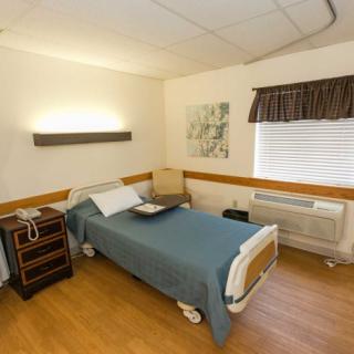 A clean and organized hospital room with a single bed and medical equipment.