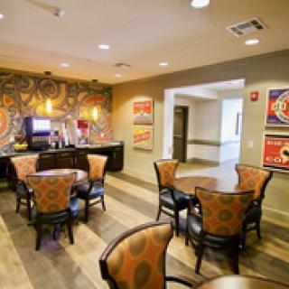 A cozy dining area with tables and chairs, decorative artwork on the walls, and a coffee machine in the corner.
