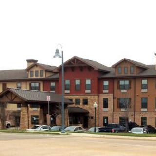 A modern hotel building with parked cars in front, showcasing a blend of traditional and contemporary architectural styles.