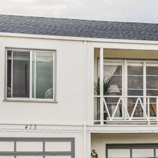 A two-story residential house with large windows and a balcony.