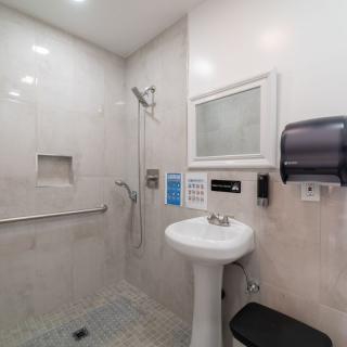 A clean, handicap-accessible bathroom with a pedestal sink and shower area.
