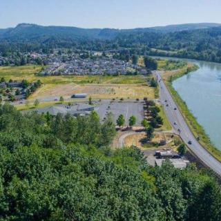 A scenic aerial view of a town nestled between lush greenery and a winding river, with distant rolling hills.